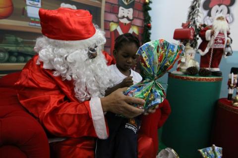 criança vê presente no colo do papai noel  #paratodosverem