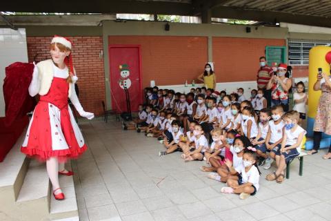 Mamãe noel está diante de várias crianças sentadas. #paratodosverem