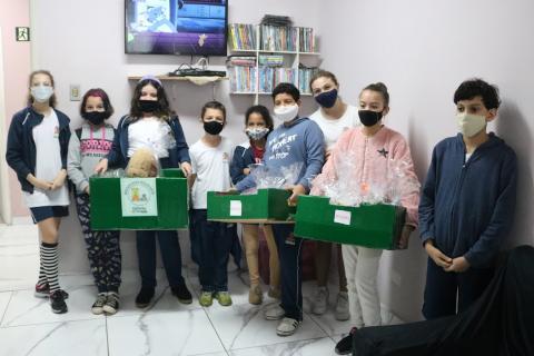 Crianças com caixas posam para foto #paratodosverem