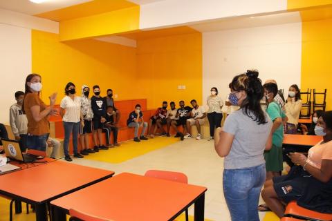 jovens em pé, e no fundo, alguns sentados, conversam #paratodosverem