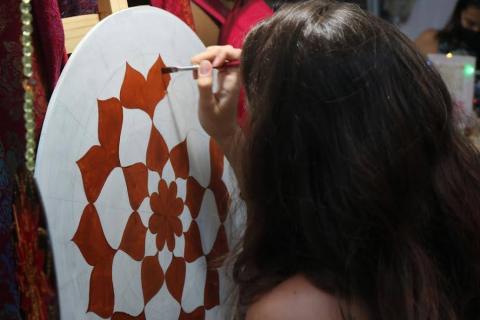 Mulher de costas para foto segura pincel e pinta mandala em tela. #paratodosverem