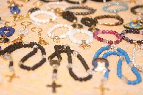 mesa com pulseiras e terços. #paratodosverem