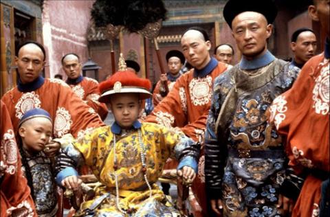 Foto ilustrativa do filme com o pequeno imperador cercado por várias pessoas. #paratodosverem
