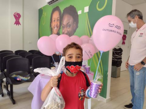 Criança com balões do outubro rosa #paratodosverem