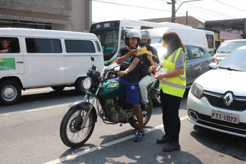 Mulher entrega panfleto para motociclista #paratodosverem