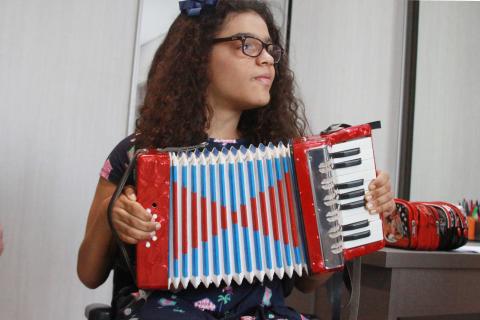 menina toca acordeão. #paratodosverem