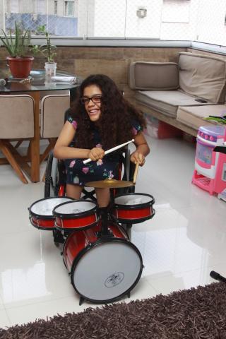 menina sentada na cadeira de rodas toca bateria, #paratodosverem