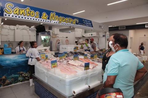 consumidores estão diante de box com peixes expostos. #paratodosverem