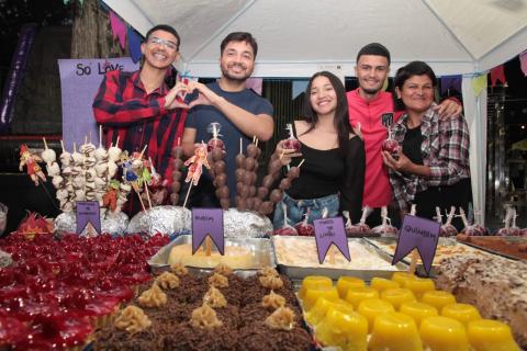 pessoas na frente de barraca de doces #paratodosverem