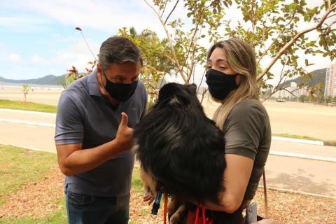 o prefeito brinca com cão que está no colo de tutora. #paratodosverem