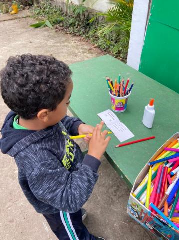 menino usa lápis colorido para desenhar. #paratodosverem
