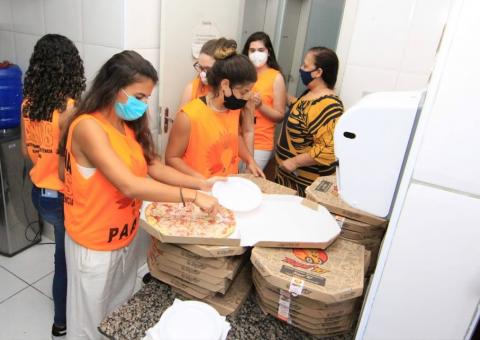 jovens mexem em caixas de pizza. Todos estão uniformazados e usando máscara. #paratodosverem