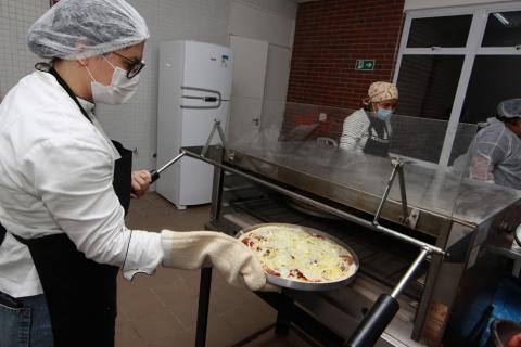 mulher coloca pizza dentro de forno. #paratodosverem