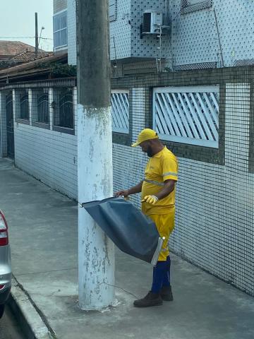 operário usando uniforme amarelo segura banner recém-removido de poste. #paratodosverem