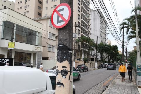 placa de proibido estacionar junto a poste que tem arte em grafite na parte de baixo. #paratodosverem