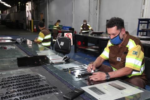 homens escolhem adesivos de tipos para serem usados nas placas de sinalização. #paratodosverem