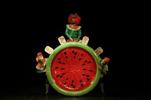 Uma pessoa vestida de melancia em uma roleta em forma de melancia #paratodosverem