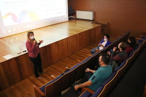 Mulher fala para pessoas em auditório #paratodosverem