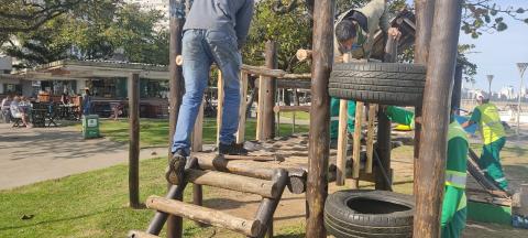 homens reparam brinquedo que tem escada de madeira e pneus. #paratodosverem