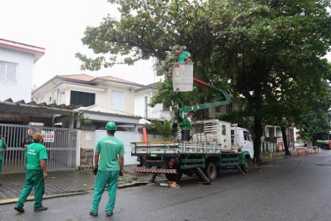 homem está no cesto de caminhão basculante. Outros homens estão na rua para auxiliar o trabalho. #paratodosverem