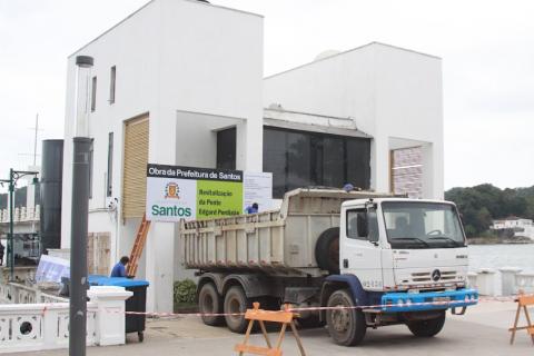 caminhão parado na fachada lateral da ponte, onde está instalada uma placa da prefeitura. #paratodosverem