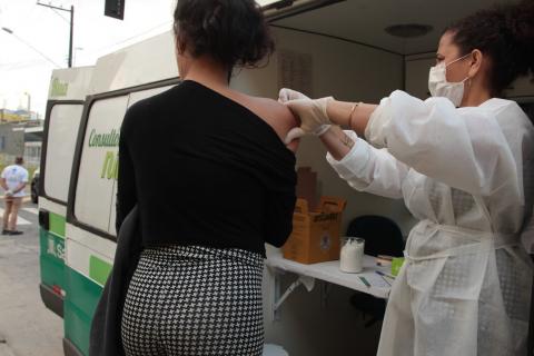 mulher, de costas para a foto, é vacinada por outra mulher. #paratodosverem