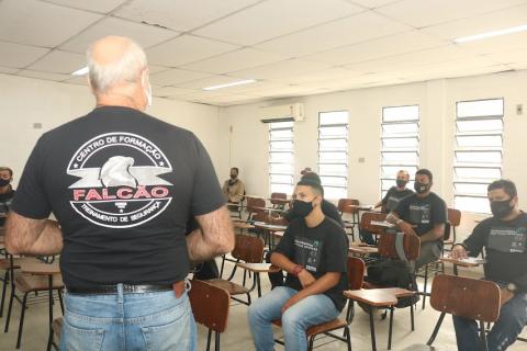Professor (de costas) explica conteúdo para alunos. #paratodosverem