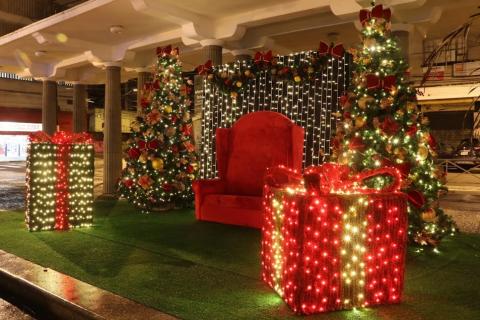 ambiente para o papai noel, com decoração de caixas de presentes, árvore de natal e poltrona