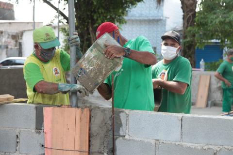 Trabalhadores empilham blocos com cimento. #Paratodosverem