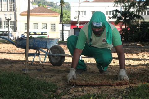 homem assenta bloco de grama sobre a terra. #paratodosverem