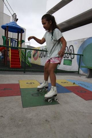 Criança anda de patins na praça. #paratodosverem