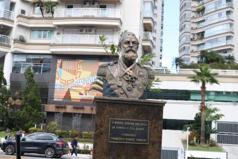 Busto do almirante Barroso em destaque, com prédios ao fundo. #paratodosverem