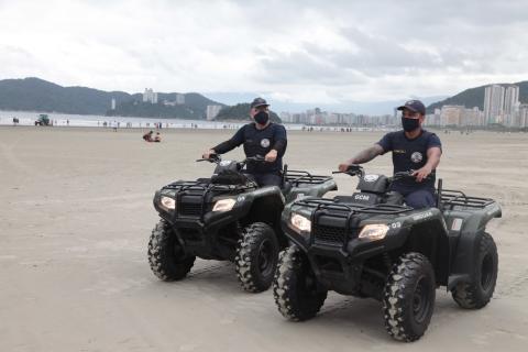 Dois guardas conduzem quadriciclos na faixa de areia. #Paratodosverem