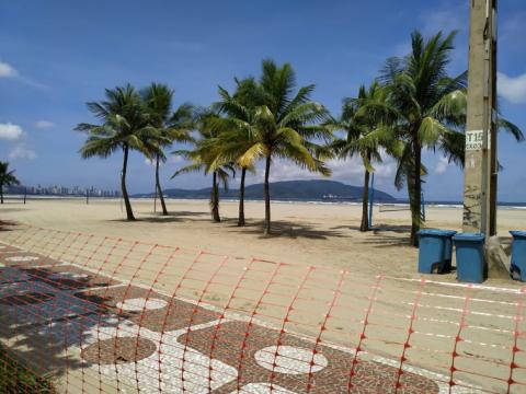 Cerquite isola acesso à faixa de areia com palmeiras ao fundo. #pracegover