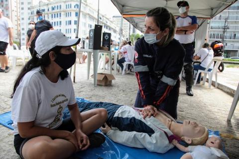 integrante do samu faz simulação de massagem cardíaca em boneco no chão. #paratodosverem