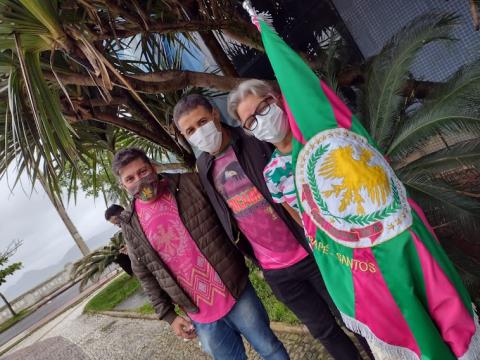 Três pessoas e bandeira de escola de samba #paratodosverem