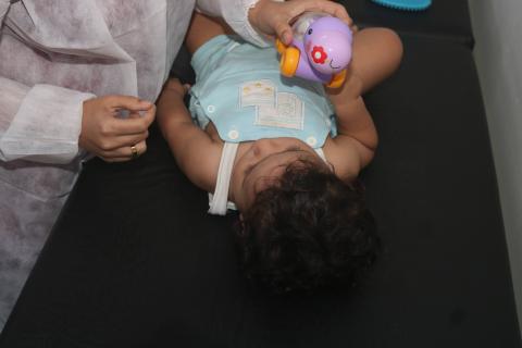 criança deitada e enfermeira  mostra brinquedo #paratodosverem