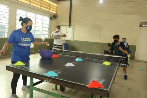Ligia dá aula de tênis de mesa para jovens. #paratodosverem