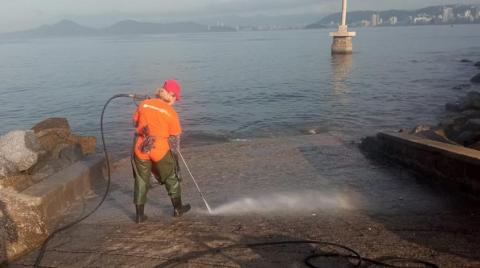 pessoa joga jato de agua em rampa com mar ao fundo #paratodosverem