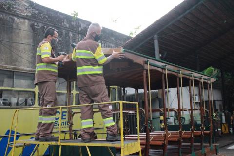 dois operários da CET, sobre um andaime retocam detalhes no reboque. #paratodosverem