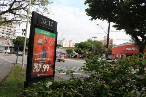 relógio em canteiro central de avenida à frente de plantas. #paratodosverem