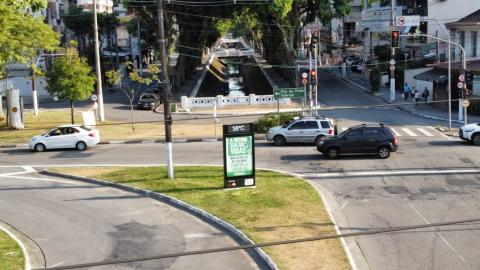 imagem por drone mostra relógio em canteiro central na confluência de avenidas. Carros passam. #paratodosverem