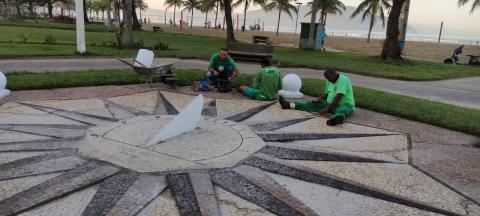 homens estão sentados no chão ajustando piso em mosaico português. #paratodosverem