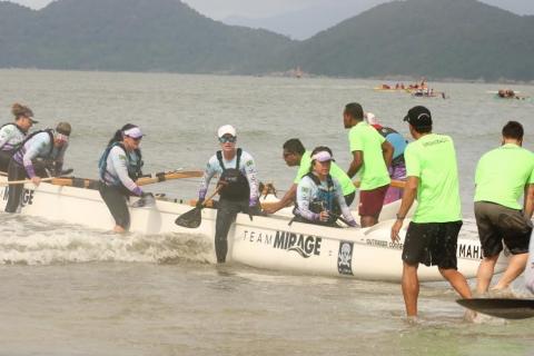 mulheres já dentro de canoa começam a remar. #paratodosverem