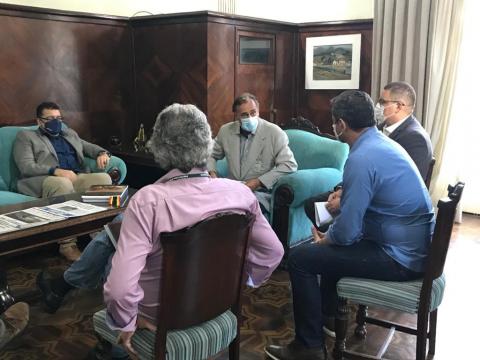 Cinco homens reunidos em torno de uma mesa. #paratodosverem