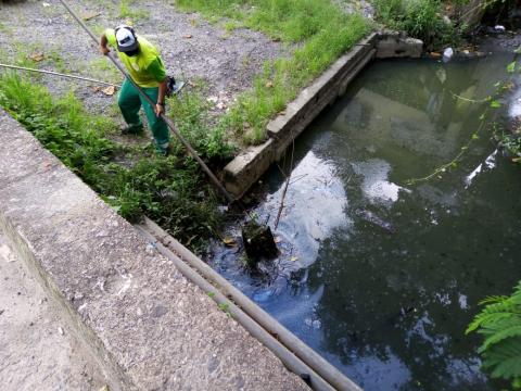 Homem remove resíduos de trecho de rio. #Paratodosverem