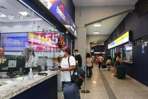 movimento em guichê de venda de bilhetes com um homem, do lado de fora, conversando com a mulher que está atrás do vidro. #paratodosverem