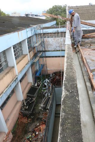 trabalhador no teto e embaixo corredor de escola em obras #paratodosverem
