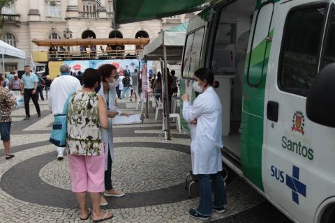 Pessoas conversam ao lado de van na praça #paratodosverem