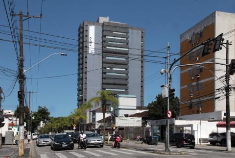 imagem da avenida com carros, motos estacionadas e prédios ao fundo #paratodosverem